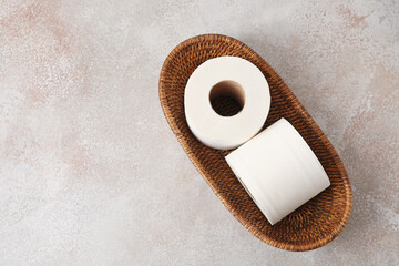 Fototapeta na wymiar Basket with rolls of toilet paper on grunge background