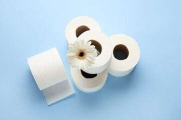 Rolls of toilet paper and flower on color background