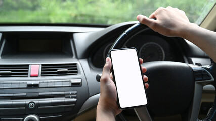 Close up view of young man using smart phone while driving car.