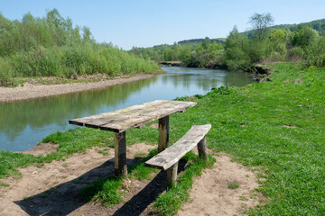 Fototapeta na wymiar Table and bench made of natural wood for a picnic on the river bank. Summer landscape, nature.