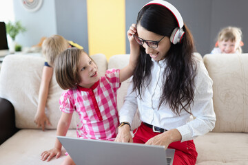 Small children prevent their mother from doing laptop work at home