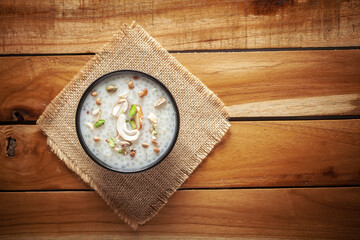 Close-up of Creamy Sabudana Kheer Garnished with dry fruits. Indian delicious dessert. Served in a black bowl. Top View on wooden background.