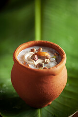 Close-up of Creamy Sabudana Kheer Garnished with dry fruits. Indian delicious dessert. Served in an earthen pot on a green fresh banana leaf.