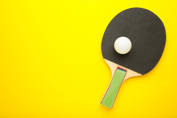 Ping pong paddle with ball on yellow background. Table tennis racket.