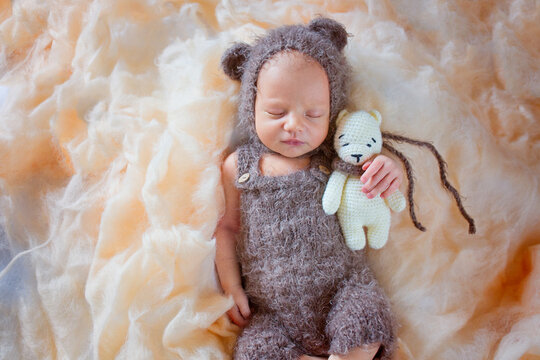 A very gentle and beautiful photo of a newborn boy in a hat with ears and a toy in his hands. Sleeping newborn baby with toy