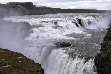 Famous Gulfoss waterfall in the Golden Circle in South Iceland. Tourists walk on the viewpoint.