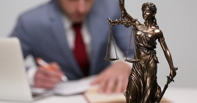businessman working at his desk and owning an impressive libra statue 