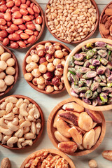 Many different nuts in wooden bowls, overhead shot on a rustic background