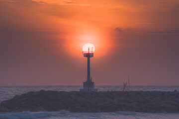 With a sunset as a backdrop, a lighthouse.