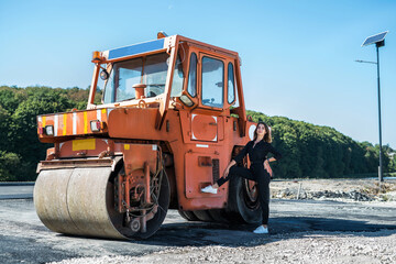 beautiful girl posing near the paver machine