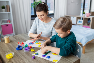 family, creativity and craft concept - mother and little son making picture of modeling clay at home