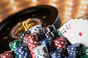 Poker Chips on gaming table, roulette wheel in motion, casino background