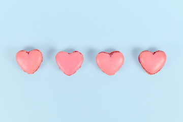 Obraz na płótnie Canvas Heart shaped French macaron sweets in a row on blue background