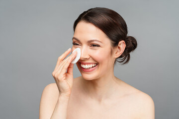 The charming woman smiles. A natural woman with good skin cleanses her face with a cotton pad. SPA, cosmetology, beauty