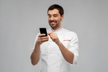 cooking, culinary and people concept - happy smiling male chef with smartphone over grey background
