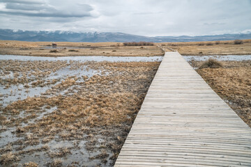 Moody panorama shot of a wooden bridge through landscapes with marshes and lakes inside Sultan Reedy (Sultansazligi) National Park, Central Anatolia, Turkey