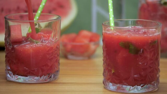 Fresh watermelon juice with mint leaves and ice cubes pouring in a glass -  Summer fruit India. Closeup shot of two glasses of tropical fruit juice / Tarbooj decorated with ice cubes and fresh mint...
