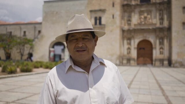 Mexican adult smiling at camera. Latin man in hat and shirt, smiling at camera. the background is from a church in Oaxaca, Mexico