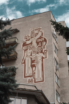 Soviet bas-relief on the theme of peace, with images of people on the wall of an old apartment building. Polyana, Transcarpathian oblast, Ukraine - may, 2021