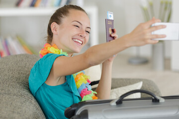 young woman taking selfie showing passport and ticket
