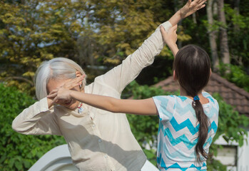 Grandchild shows her asian grandmother how to dab. Outdoors, summer