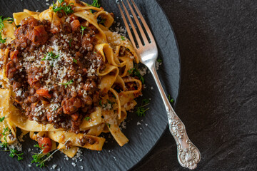 Vegetarian bolognese cooked with lentils and served with pasta on dark background 