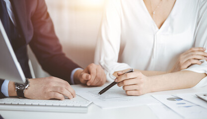 Unknown businessman and woman discussing contract in sunny office, close-up.Business people or lawyers working together at meeting