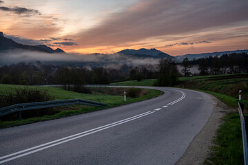 An asphalt road in the mountains during a beautiful, foggy and sunny morning