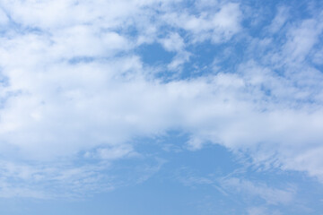 Blue sky with fluffly white scattered clouds day time landscape background.