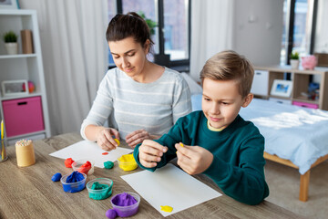 Obraz premium family, creativity and craft concept - mother and little son playing with modeling clay at home