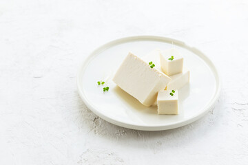 Pieces of tofu cheese with micro greens on a light plate. Horizontal orientation, copy space.