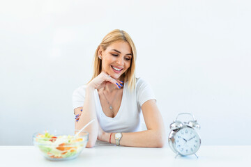 Young woman holding clock and Healthy food of salad Intermittent fasting concept. Time to lose weight , eating control or time to diet concept.