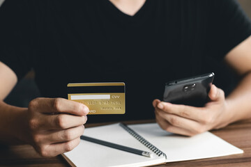 Young man using smart phone and credit card for shopping online in coffee shop cafe.