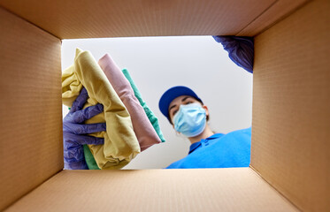 home delivery, shipping and pandemic concept - woman in protective medical mask and gloves packing...