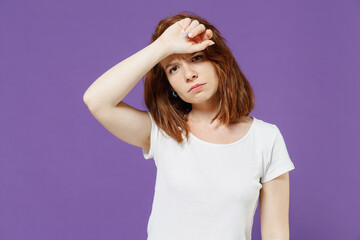 Young tired exhausted troubled sick ill confused caucasian woman 20s wear white basic blank print design t-shirt put hands on head having headache isolated on dark violet background studio portrait