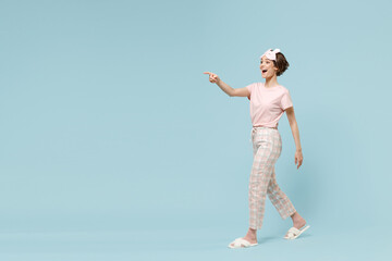 Full length young woman in pajamas jam sleep eye mask rest relaxing at home point index finger...