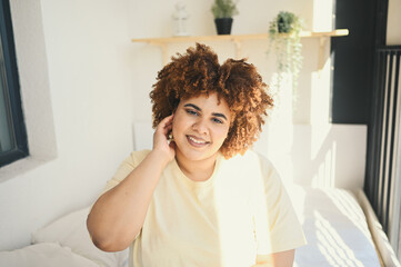 Fototapeta na wymiar Beautiful happy curvy plus size African black woman afro hair posing in beige t-shirt and underwear on sunny balcony bedroom. Body imperfection, body acceptance, body positive and diversity concept.