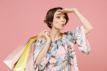 Young woman with short hairdo wear trendy stylish blouse holding package bags with purchases after shopping keep hand at forehead look far away distance seek isolated on pastel pink background studio.