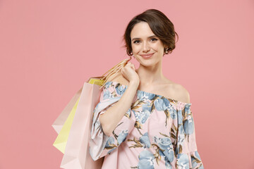 Young excited smiling caucasian happy woman with short hairdo wear trendy stylish blouse holding package bags with purchases after shopping look camera isolated on pastel pink color background studio.
