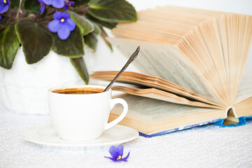 a cup of black coffee on a white table with an open book