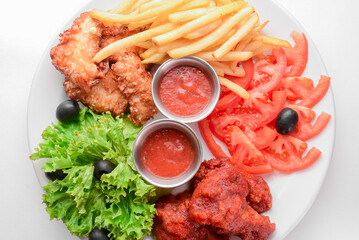 Roasted chicken wings and French fries isolated over white background. Served with fresh lettuce salad