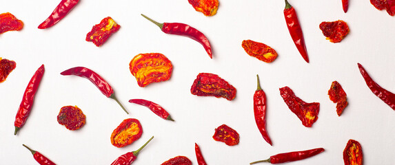 Peppers and tomatoes banner background. Dried hot chili peppers and red sun-dried tomatoes on a white plate. Spices and vegetables food minimal flat lay background concept - obrazy, fototapety, plakaty