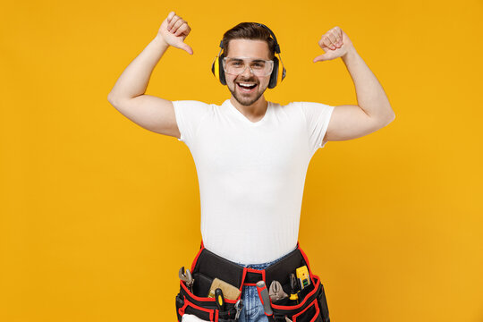 Young employee handyman man in protective point thumb finger on antinoise headphones isolated on yellow background studio portrait Instrument accessories renovation apartment room Repair home concept.