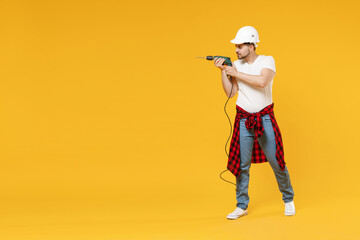 Full length young fun employee handyman man in protective helmet hardhat glasses use electric drill isolated on yellow background Instruments accessories renovation apartment room Repair home concept.