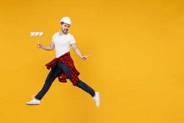 Fototapeta na wymiar Full length young employee handyman man in t-shirt using paint roller jump high point finger aside isolated on yellow background Instruments accessories renovation apartment room. Repair home concept.