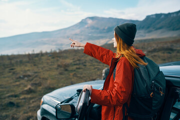 woman hiker in the mountains on nature near the car with a backpack on the back