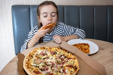 The little girl appetizingly eats a slice of pizza.