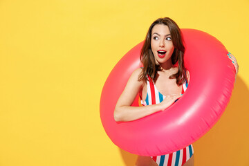 Happy fun young sexy woman slim body wear striped red blue one-piece swimsuit hold pink inflatable ring isolated on vivid yellow color background studio Summer hotel pool sea rest sun tan concept