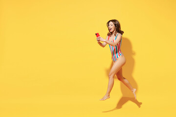 Full length fun happy sexy woman slim body wear striped red blue swimsuit jump high air run hold...