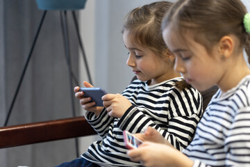 Two little girls playing games on phones.